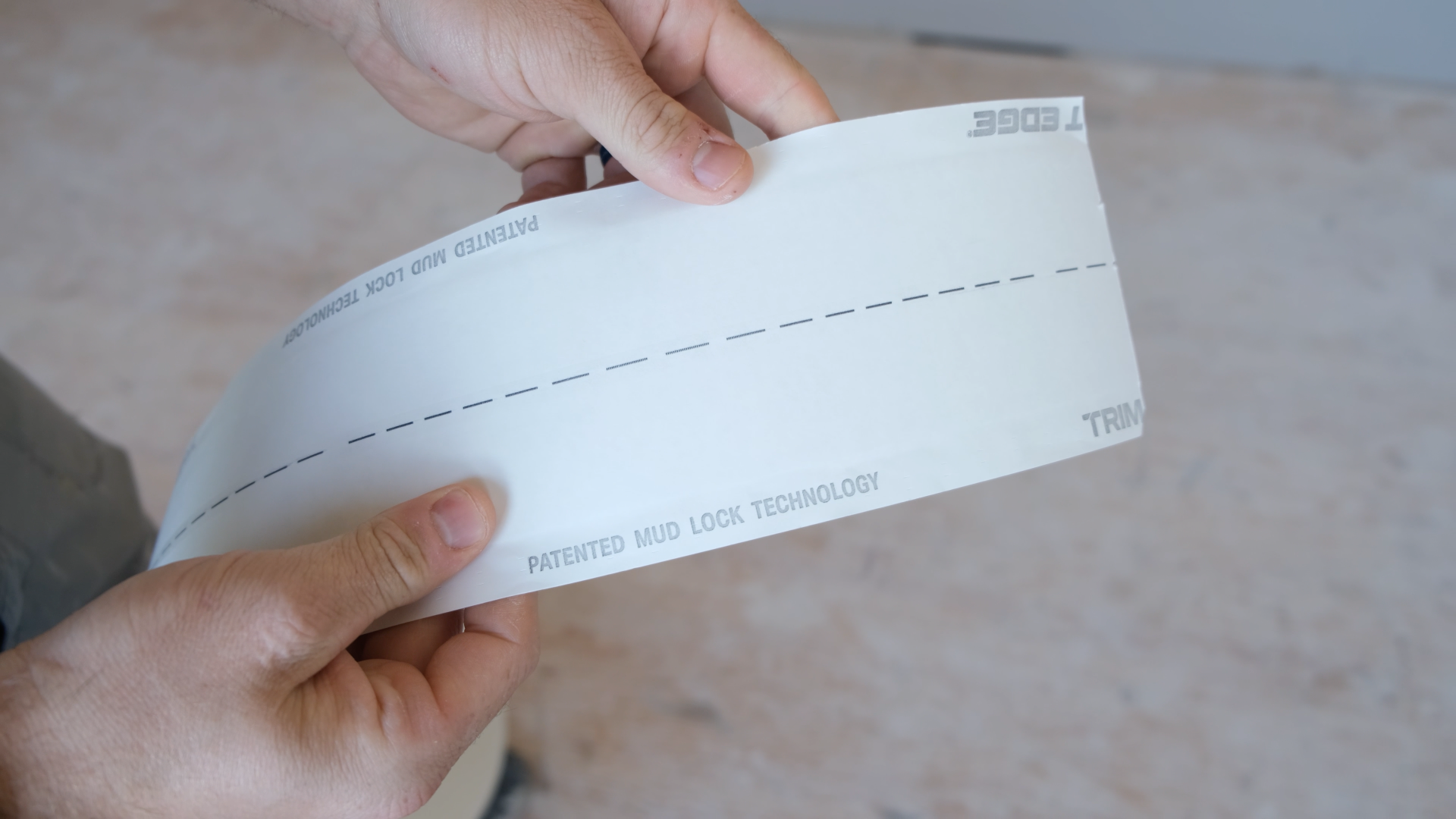 A contractor holds a piece of a rolled corner bead, Fast Edge Roll