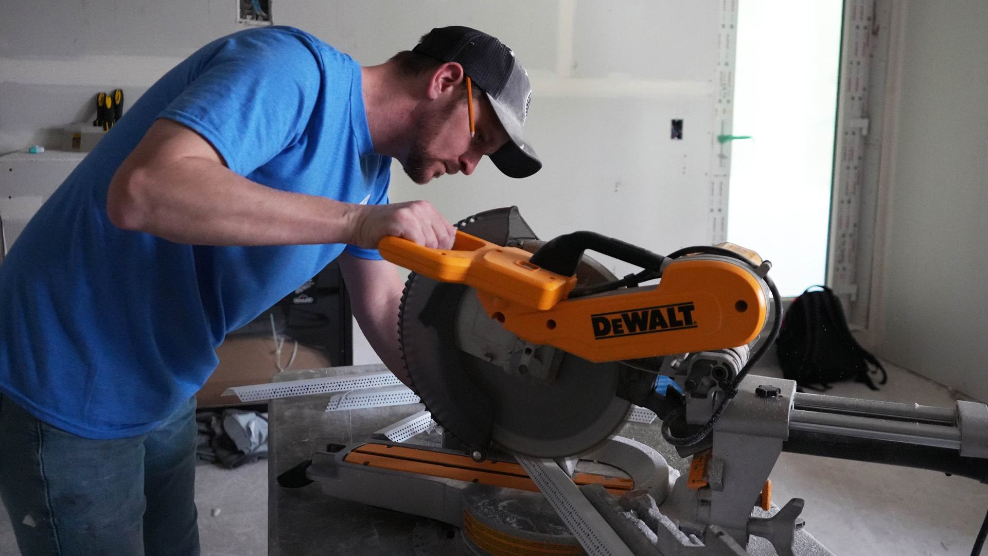 This image depicts a Trim-Tex worker using a saw for cutting corner bead.